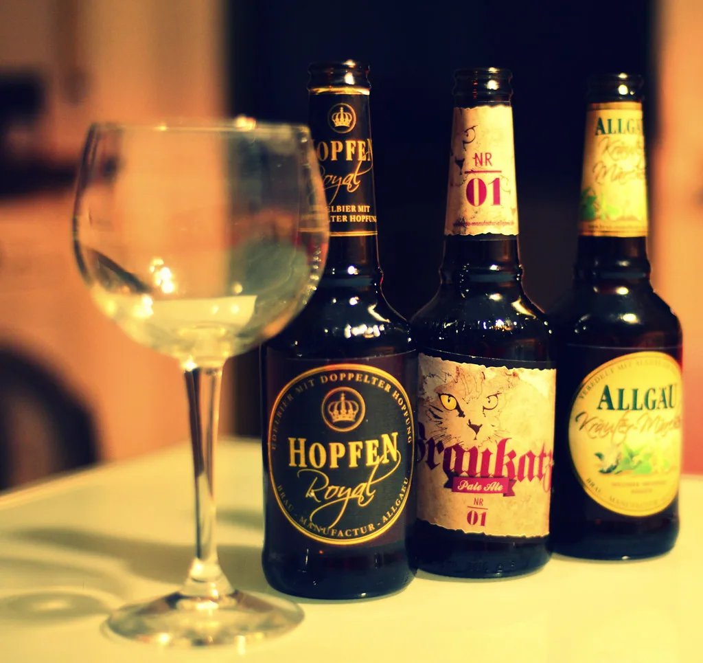 Bottles of Allgäu beer beside a glass.