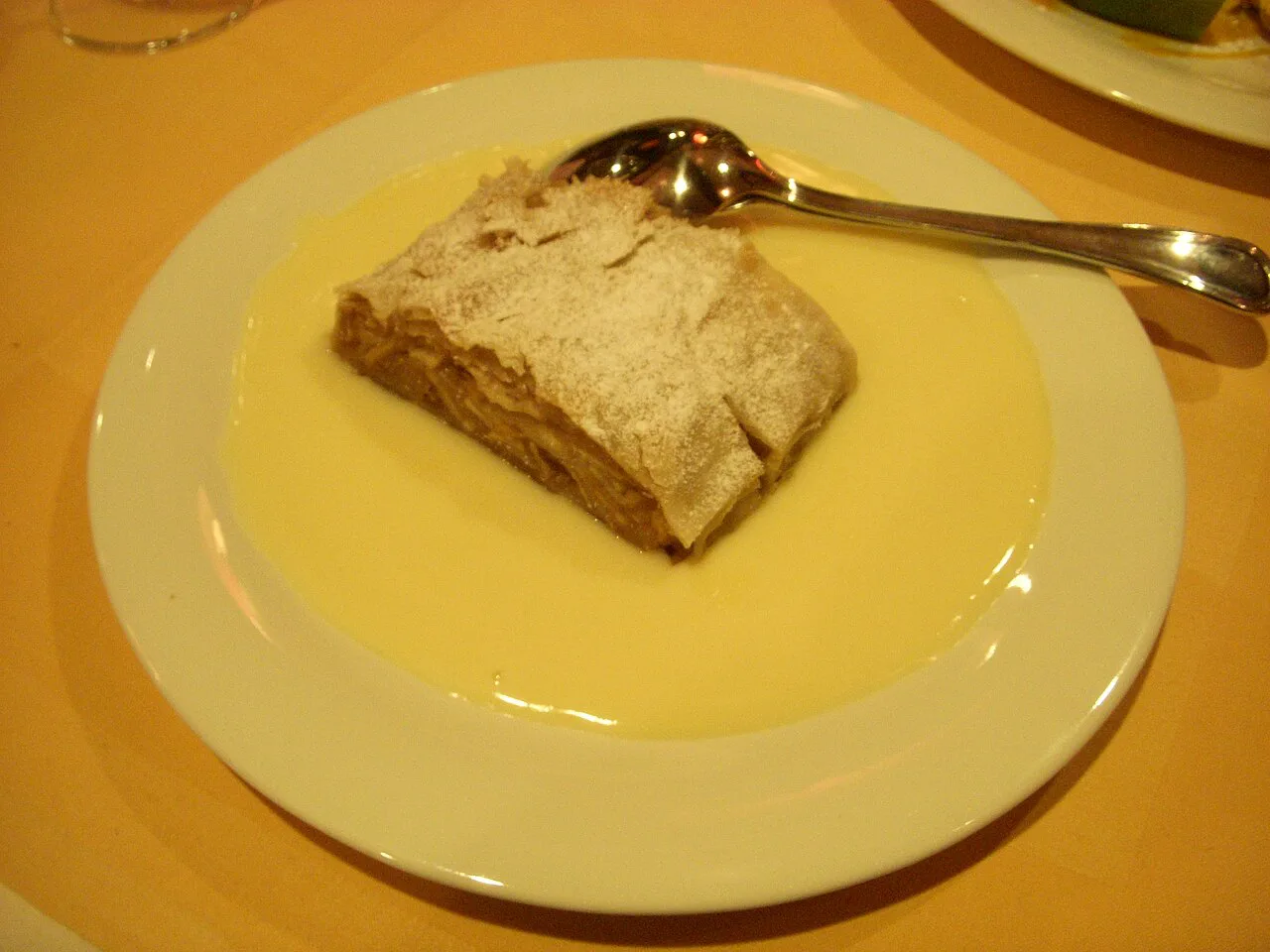 A slice of apple strudel in vanilla sauce.