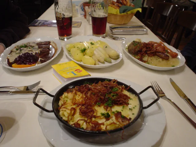 A table of hearty Bavarian dishes with a pan of cheese spaetzle.