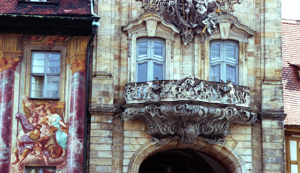 A frescoed baroque facade with an ornate balcony in Bamberg's old town.