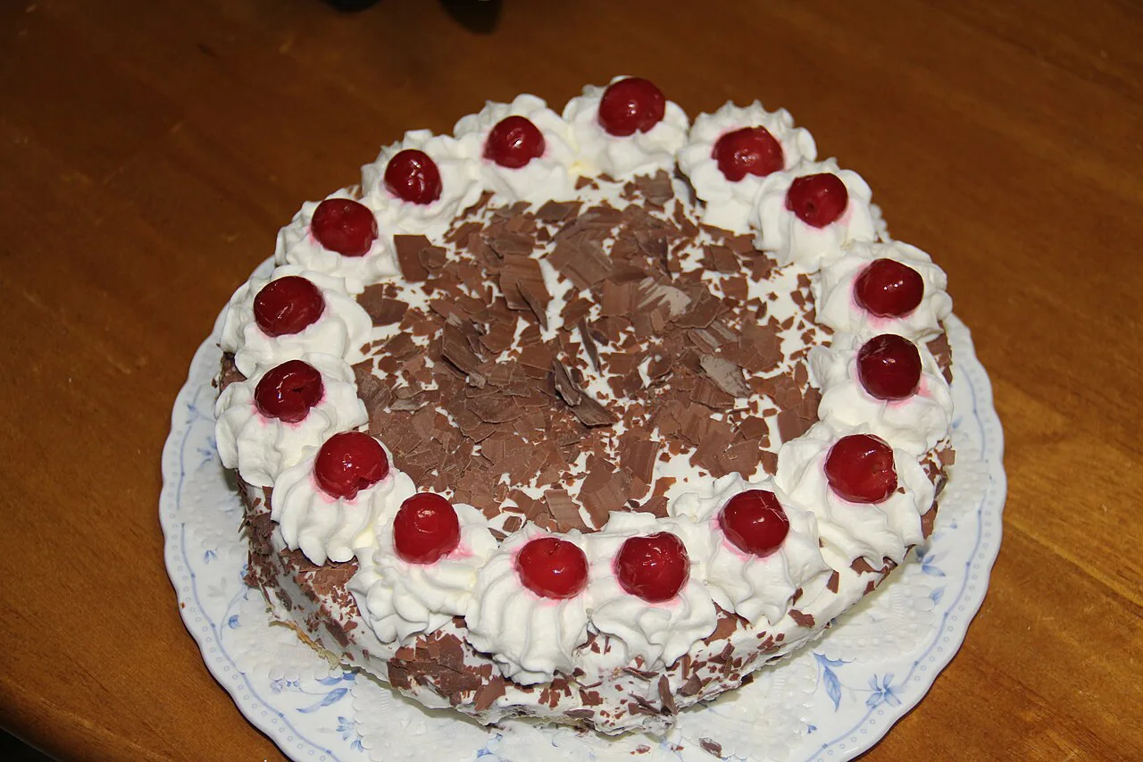 A whole Black Forest cake decorated with cherries and chocolate shavings.