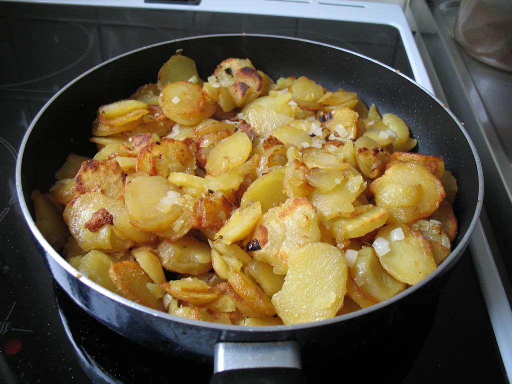 Bratkartoffeln frying in a pan.