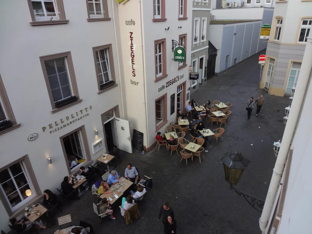 Sidewalk café tables on a square in Trier, seen from above.