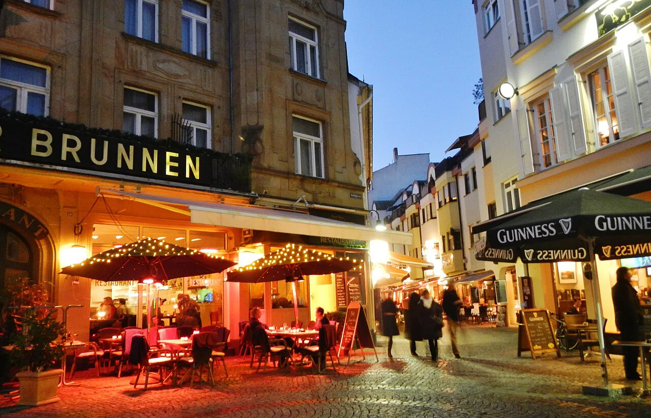 Outdoor dining tables at the Hotel Goldener Brunnen in Wiesbaden at night.