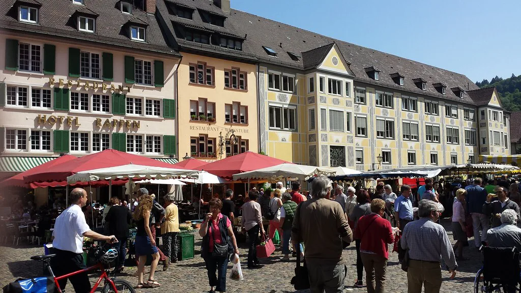 Market stalls and shoppers on a square in the old town, Freiburg.