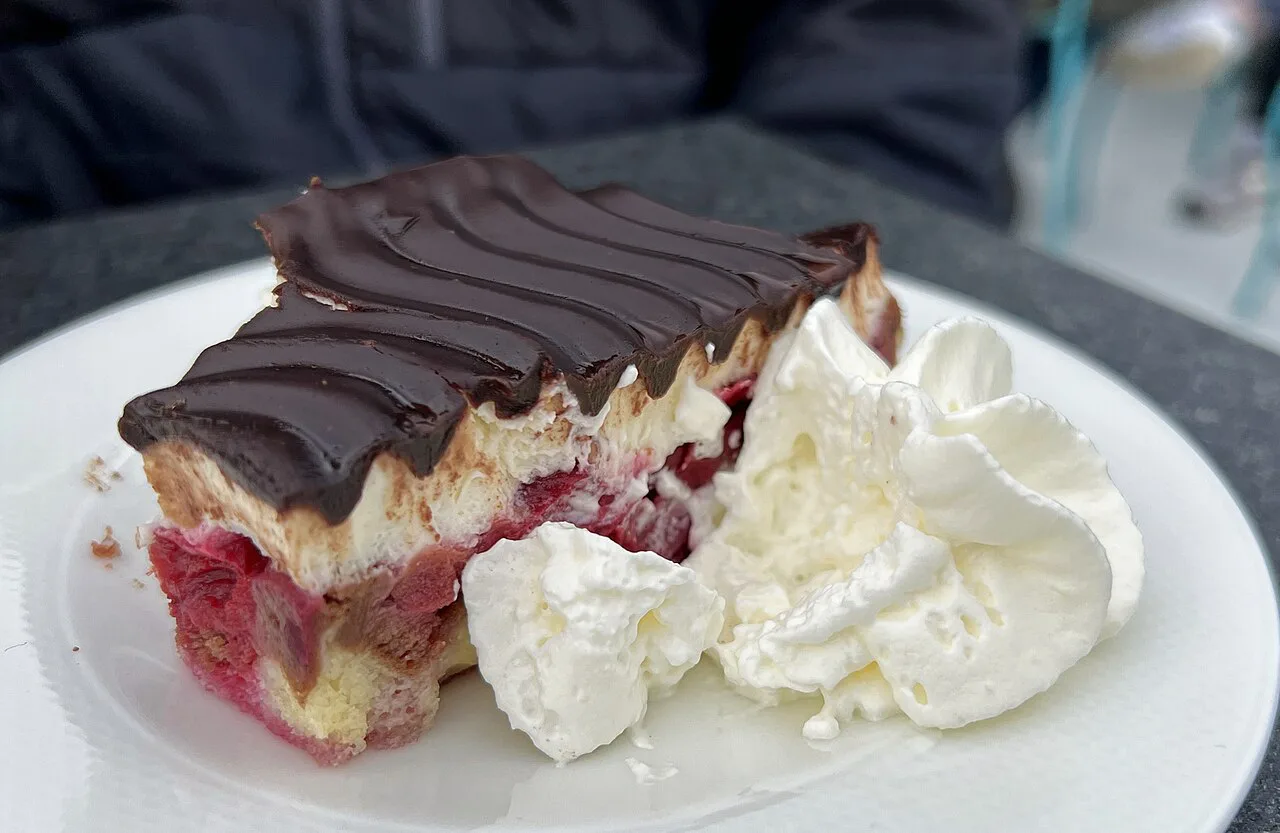 A slice of Donauwelle cake with whipped cream.