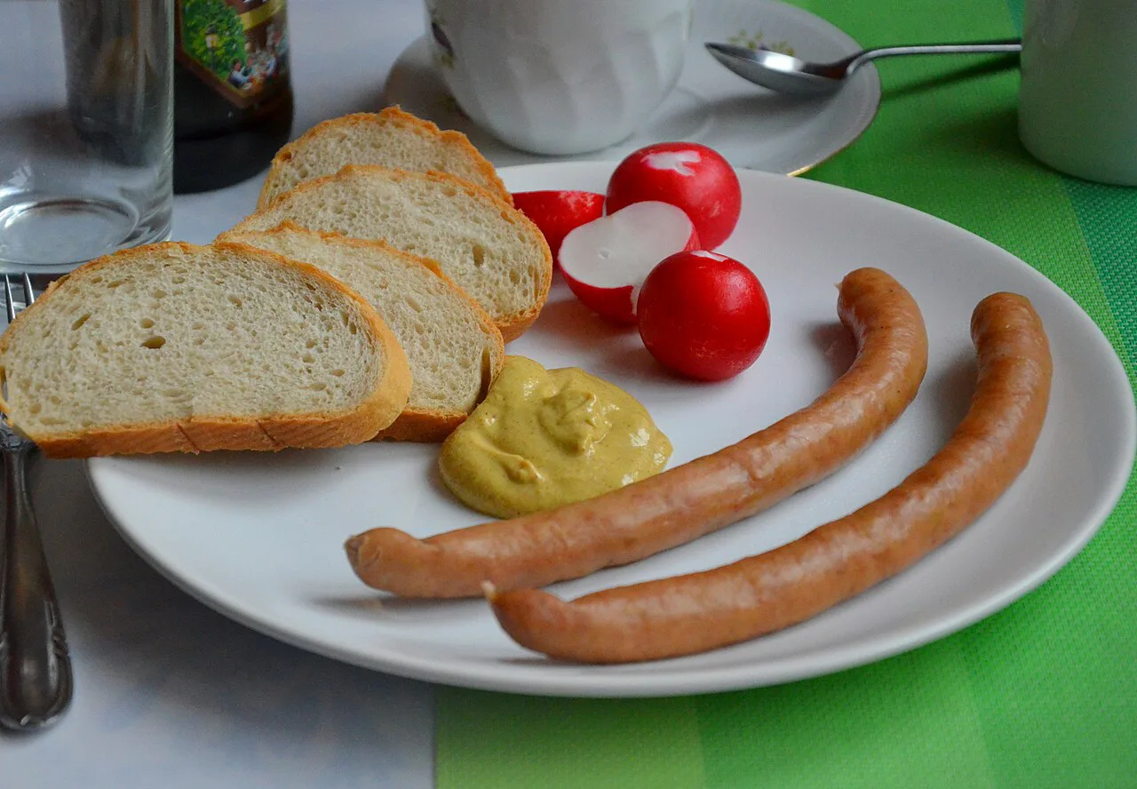 Frankfurter sausages with mustard, bread and radishes.