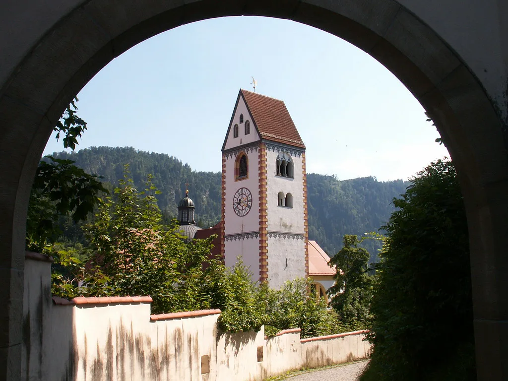 A church tower seen through a stone archway in Füssen.