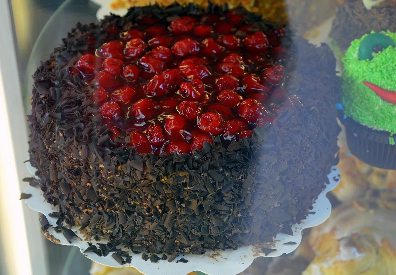 A small Black Forest cherry cake topped with cherries.