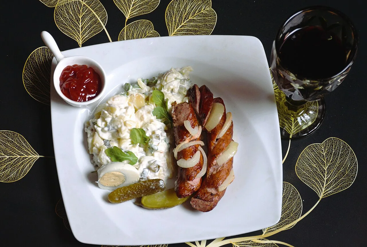 Bratwurst served with potato salad, pickles and ketchup.