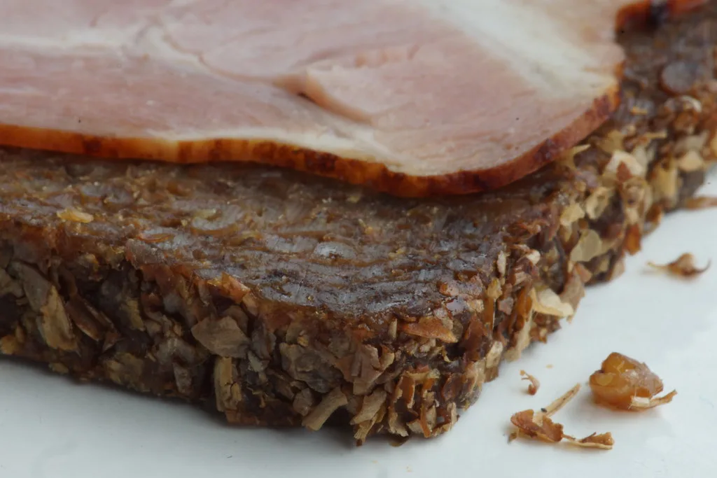 Dense dark rye bread topped with sliced pork belly.