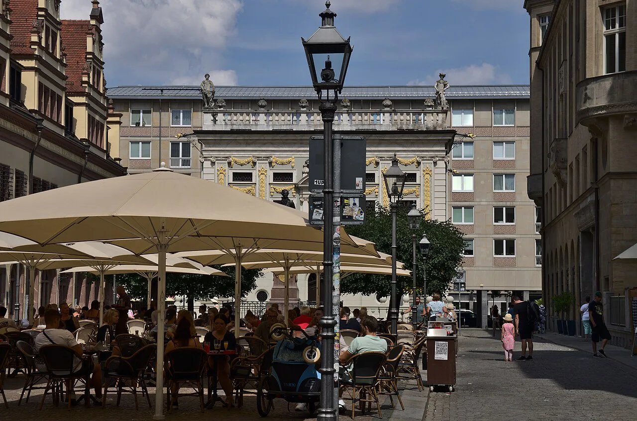 Café tables under umbrellas on the Naschmarkt by the Old Stock Exchange, Leipzig.