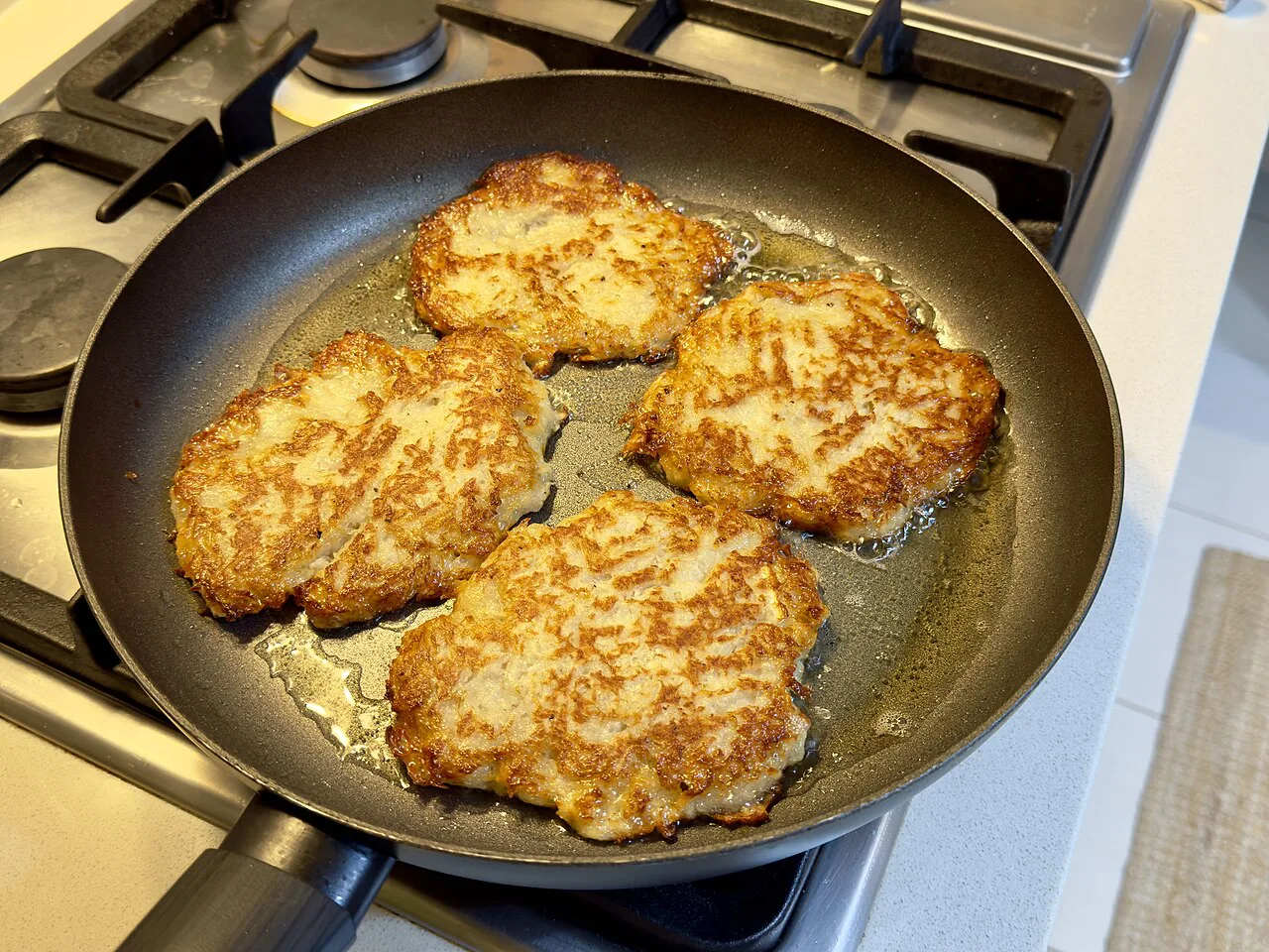 Potato pancakes frying in a pan.