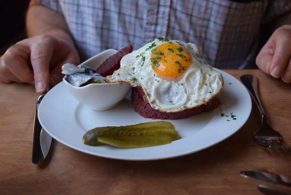 A small portion of labskaus with a fried egg, herring and a pickle, Hamburg.