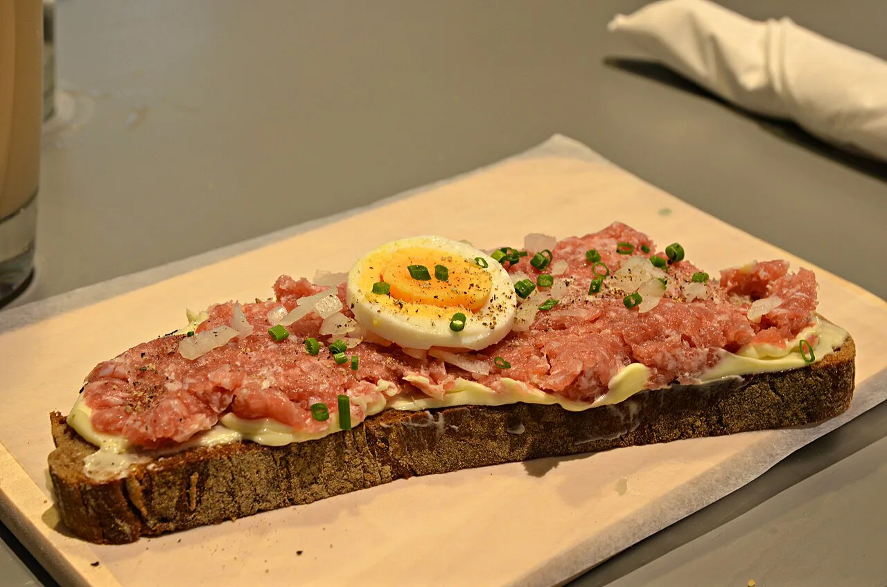 Mett, seasoned raw minced pork, on bread with egg and chives.