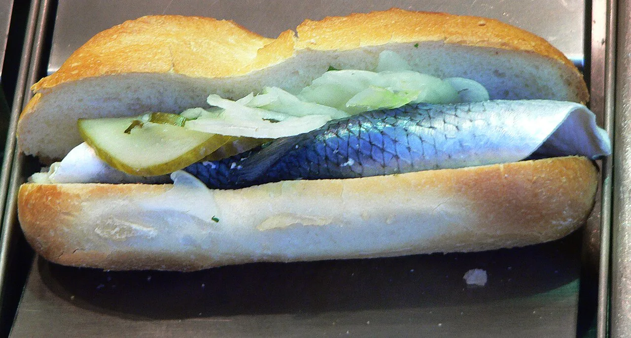 A Fischbrötchen filled with pickled herring and onion.