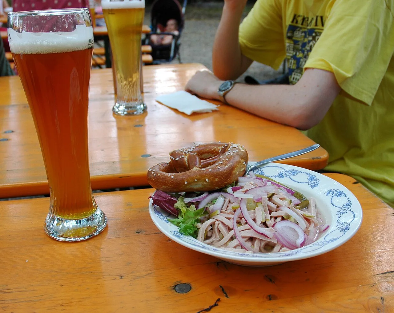 A beer-garden Brotzeit with a wheat beer, a pretzel and a plate of cold cuts.