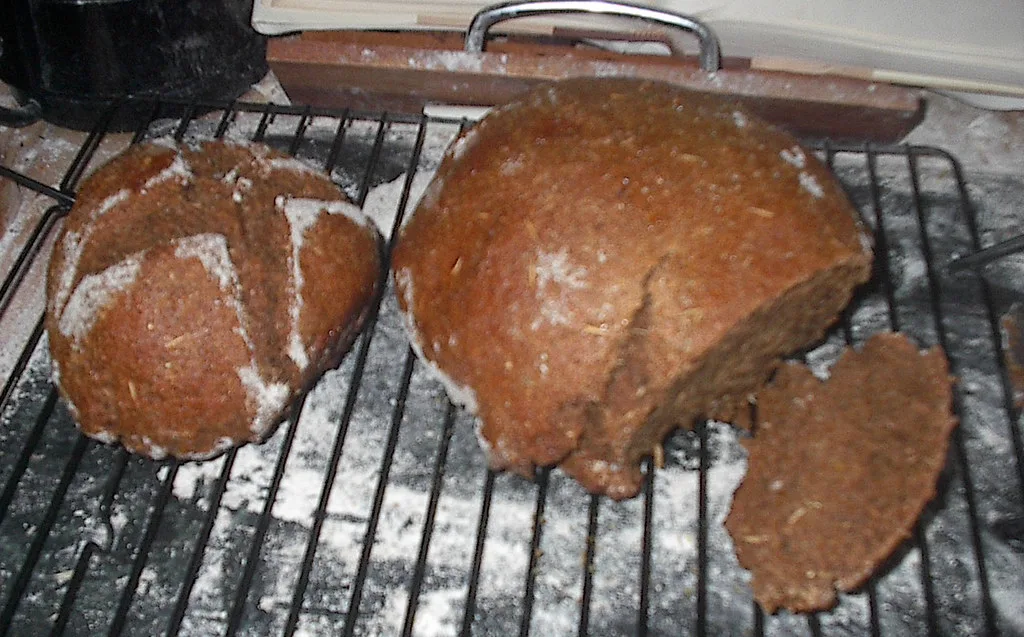 Homemade pumpernickel loaves cooling on a rack.