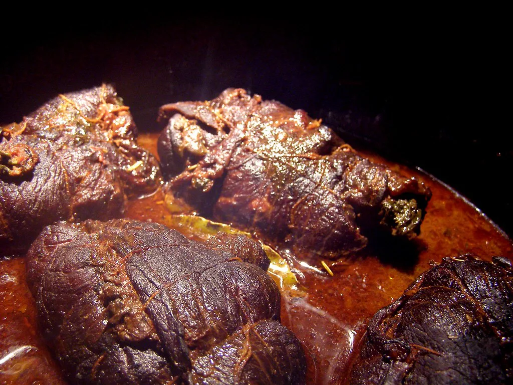 Beef rouladen braising in gravy.