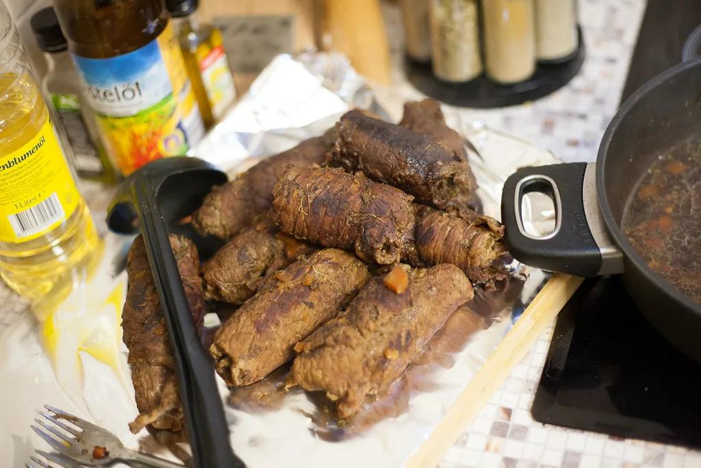 Beef rouladen browning in a pan.