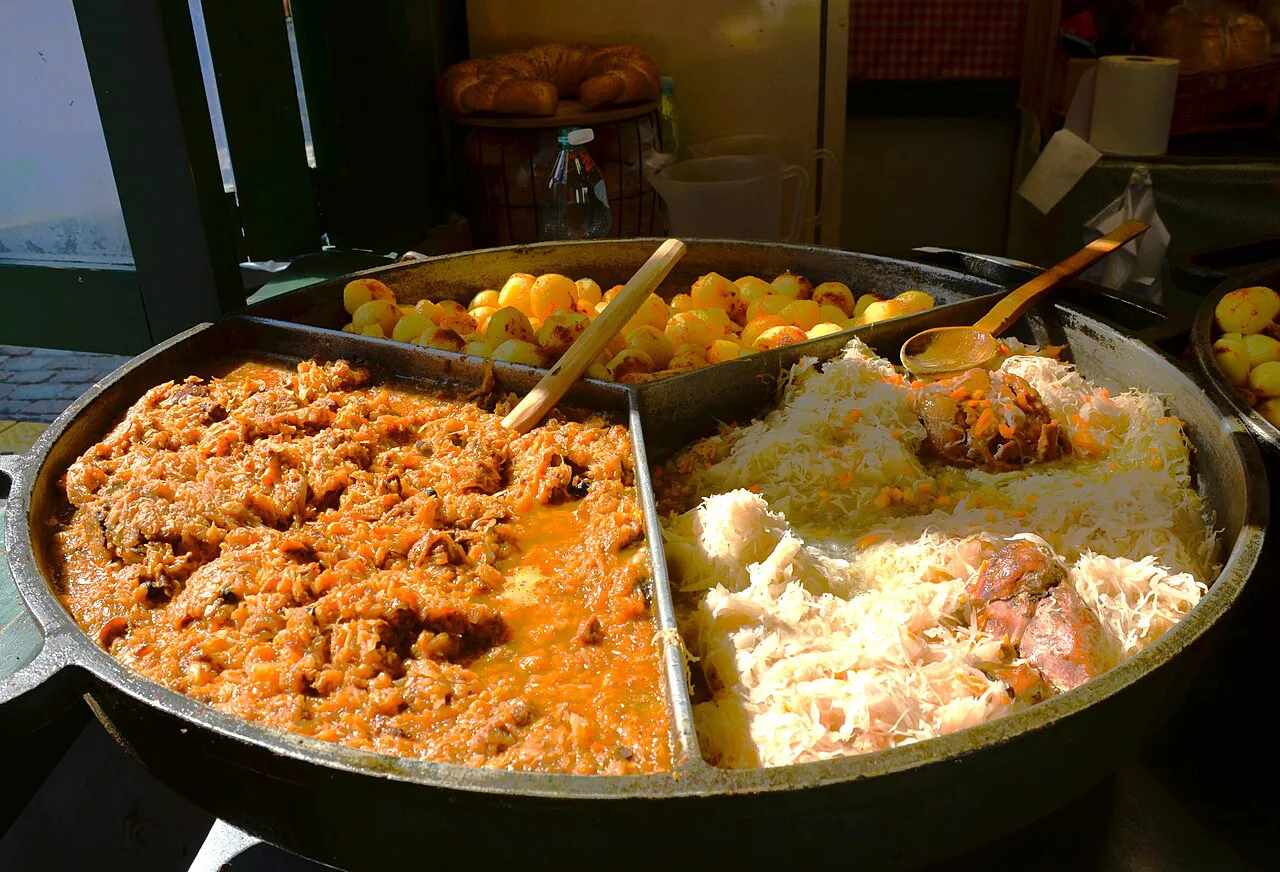 Eisbein in sauerkraut, bigos and baked potatoes in a serving pan.