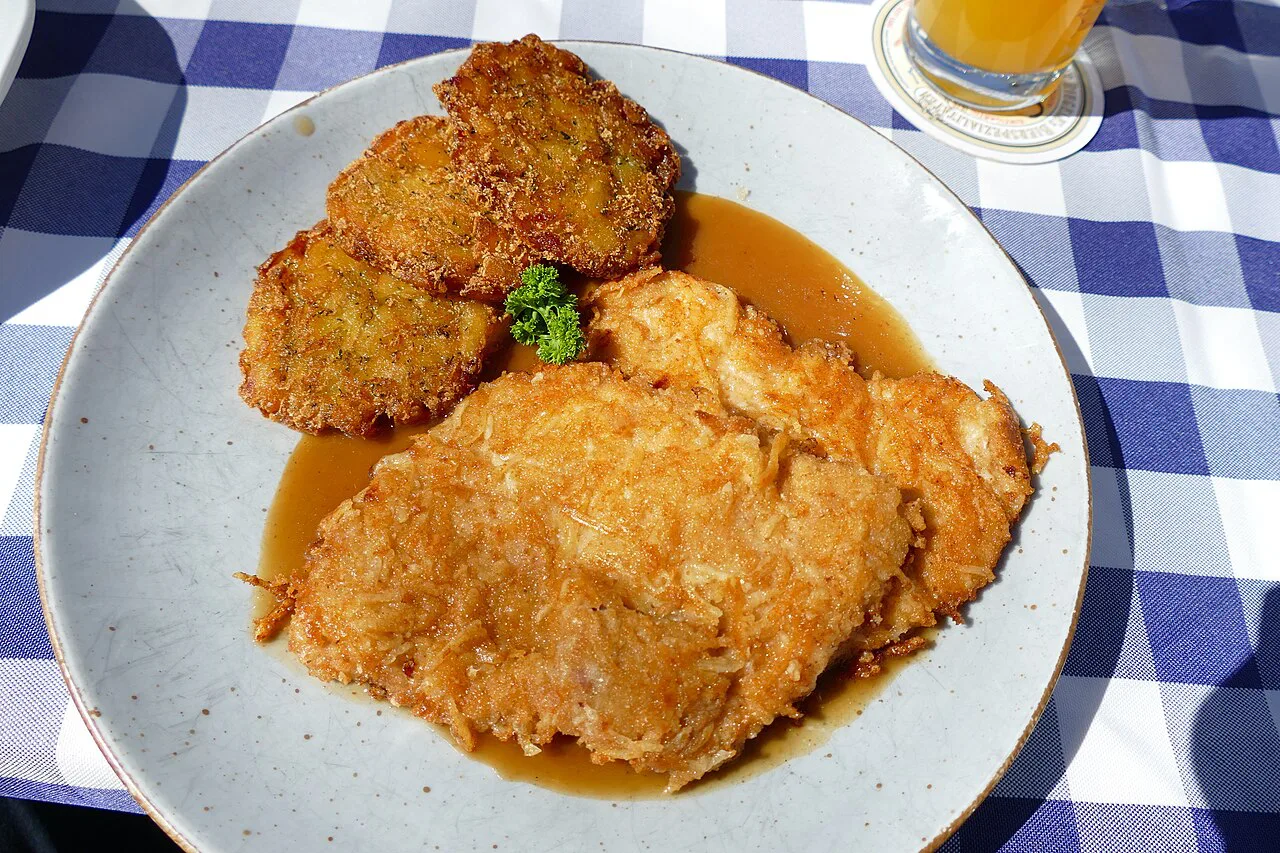 Allgäuer schnitzel topped with cheese, with herb hash browns, at a restaurant in Anhausen, Bavaria.