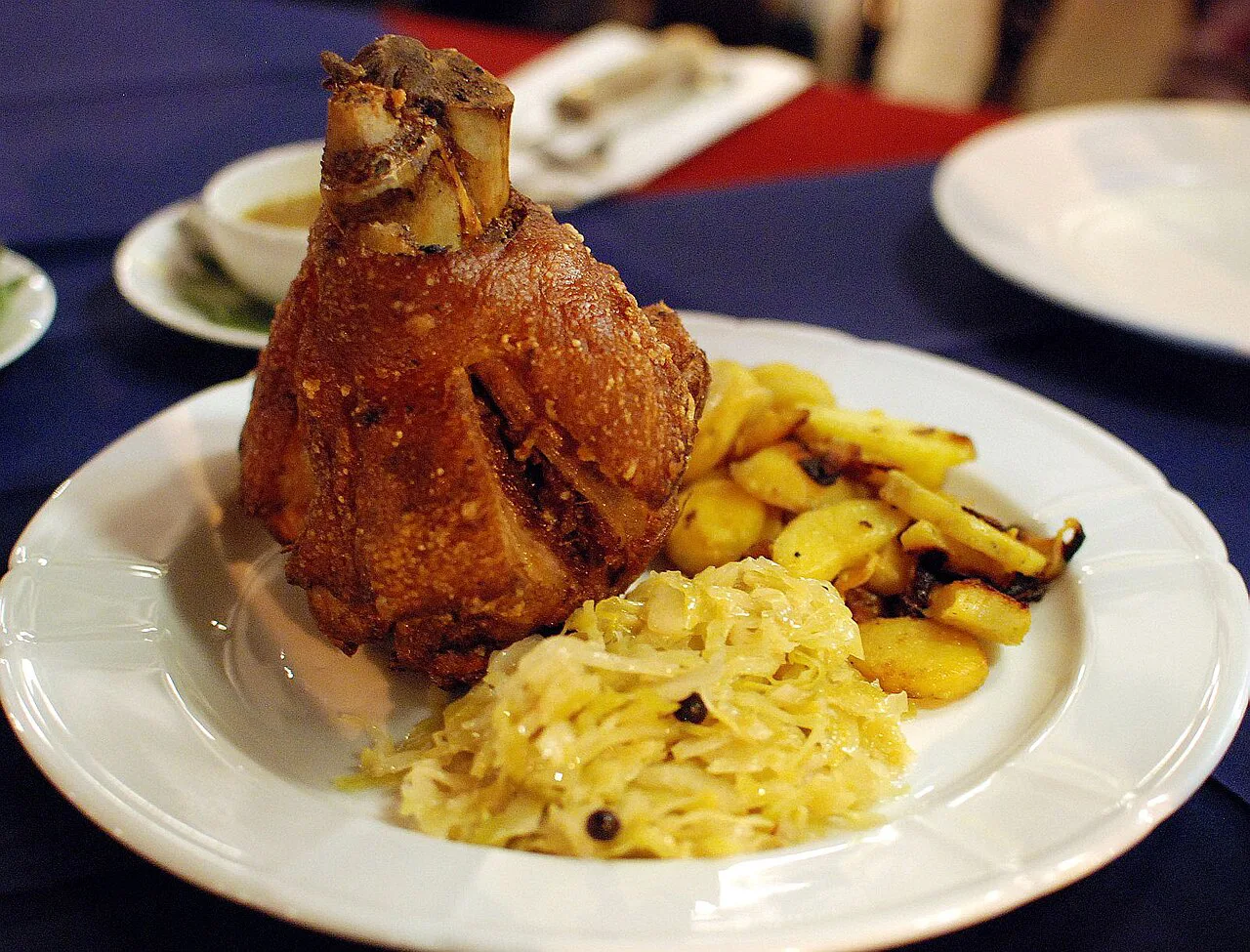 Grilled Schweinshaxe with sauerkraut and fried potatoes.