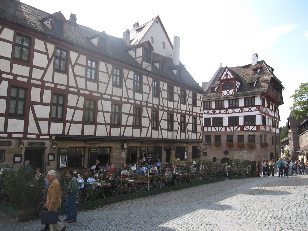 Outdoor café tables by half-timbered houses on the square at the Tiergärtner Gate, Nuremberg.