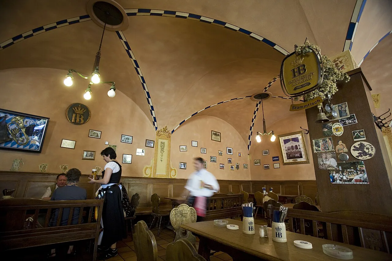 Staff serving tables in the vaulted dining room of the Hofbräukeller, a traditional Bavarian restaurant in Munich.