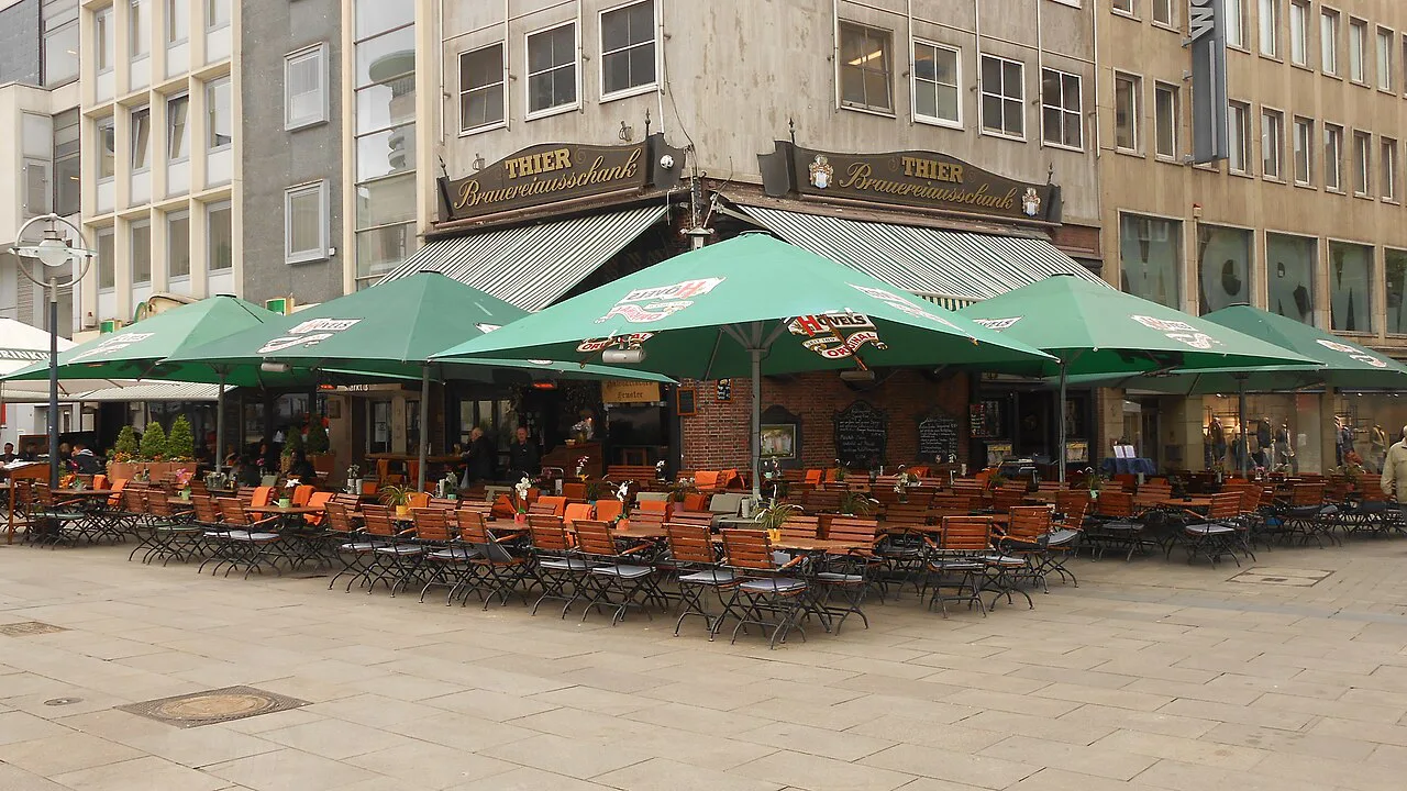 The terrace of Zum Alten Markt under green umbrellas, Dortmund.